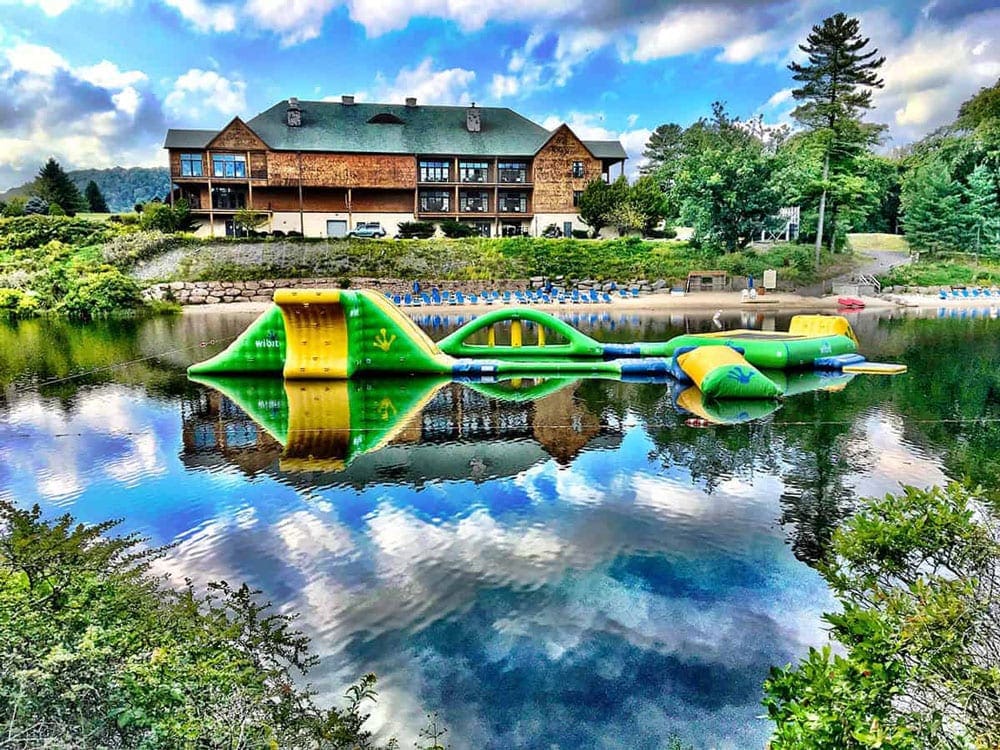 A large inflatable rests on the lake with Skytop Lodge in the background.