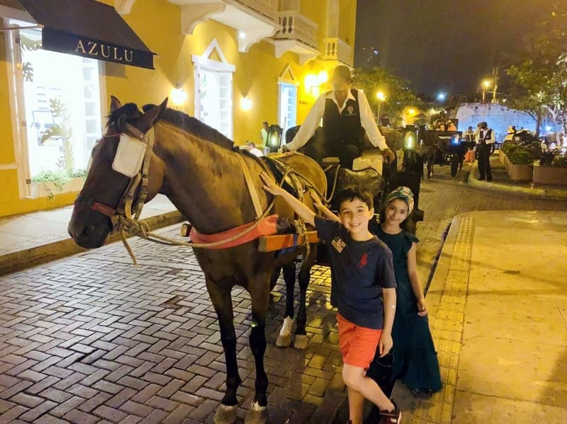 Two kids pet a horse as part of a horse-drawn carraige ride in Cartagena.