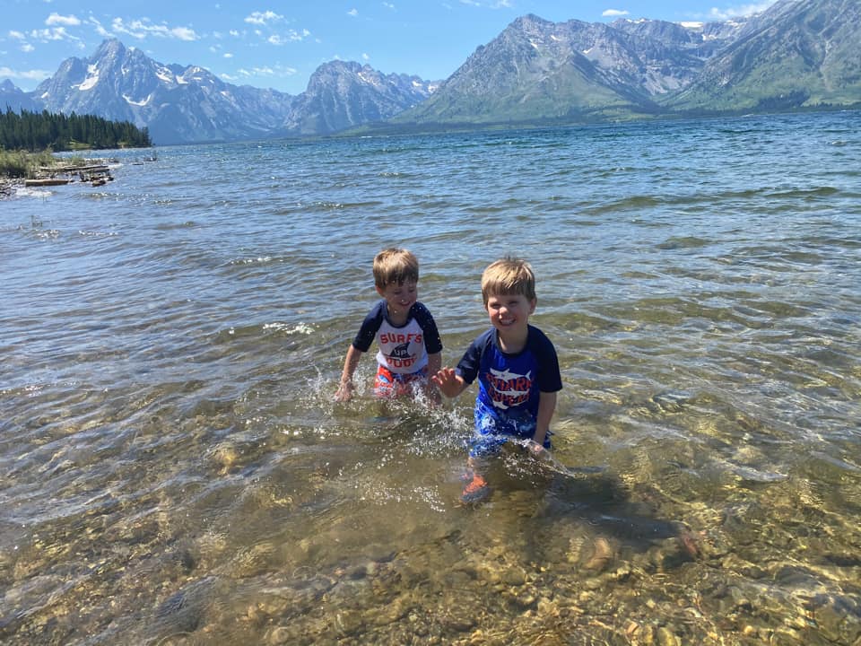 Two kids splash in Jenny Lake, one of the best things to do in Grand Tetons National Park with kids.