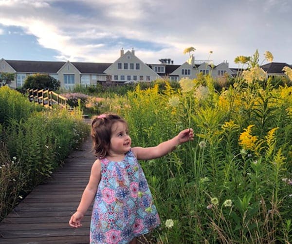 Girl touching flower in a resort in Maine.