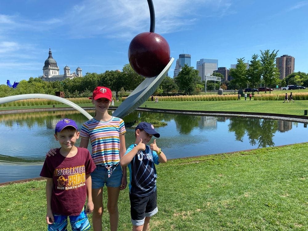 Three kids stand in front of the Spoon and Cherry art installation in Minneapolis, one of the best places to explore in the Twin Cities with kids.