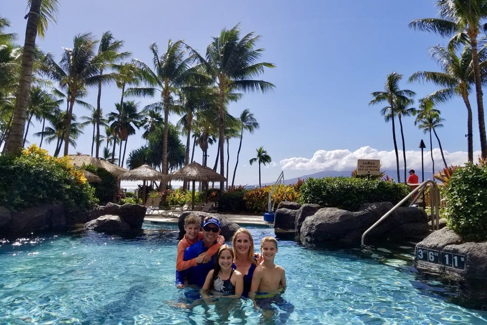 A family of five poses together while enjoy the Hyatt Residence Club pool on a sunny day.