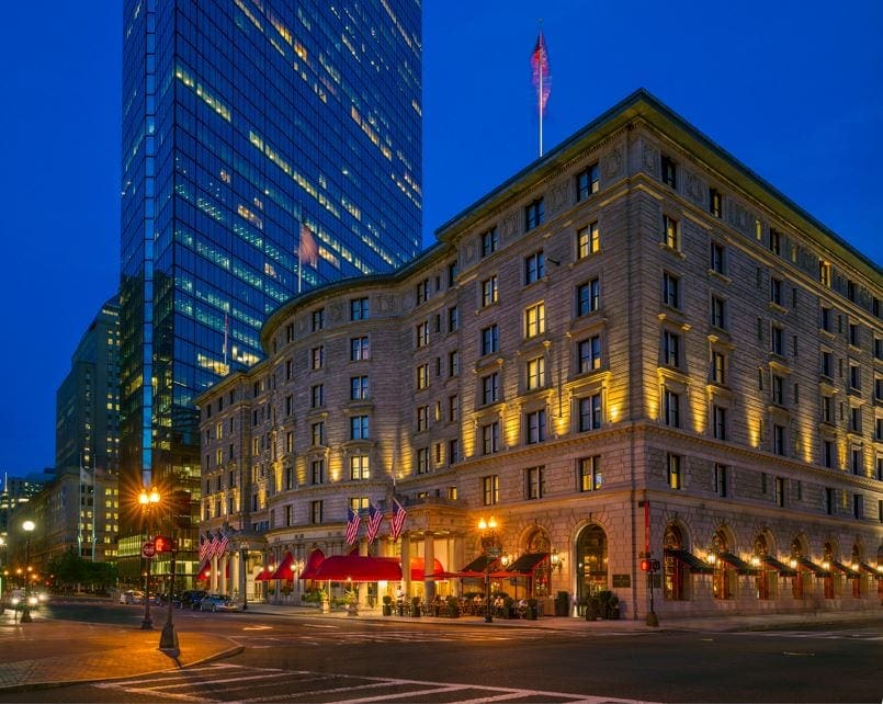 A view of the immense Fairmont Copley Plaza, one of the best hotels in boston for families, from the street corner at night.