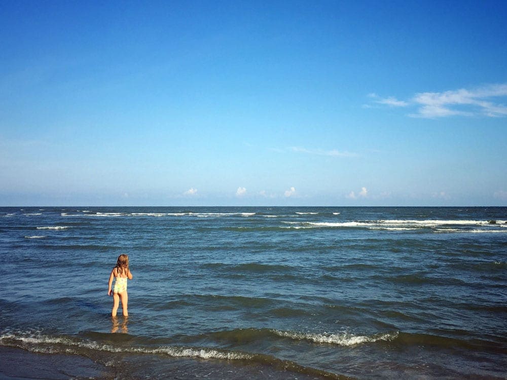 A young child plays in the water off the coast of Hilton Head, one of the best East Coast summer destinations for families.