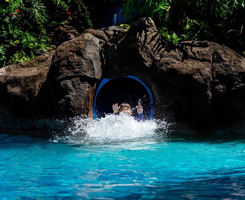 A young boy splashes through water at the end of a water slide at Hyatt Regency Maui Resort And Spa.