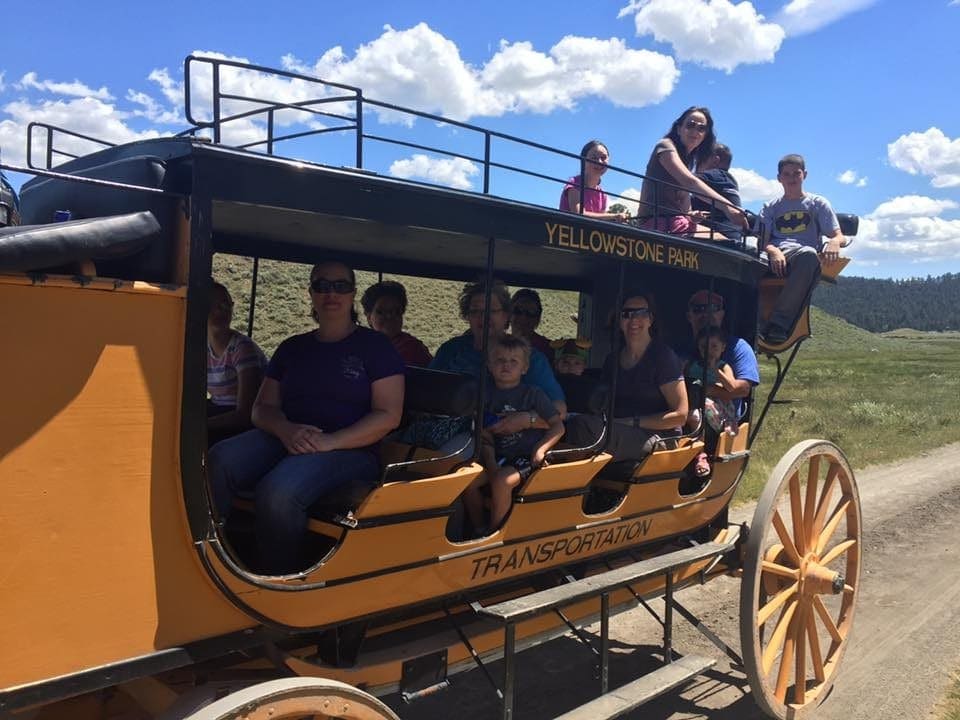 Several people look out from a yellow coach within Yellowstone National Park.