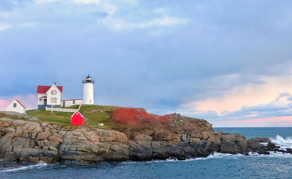 A bright lighthouse rests ashore near York, Maine.