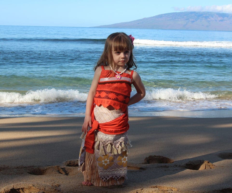 Girl dressed in Hawaii dress on the beach in Maui, one of the best islands in Hawaii for kids.
