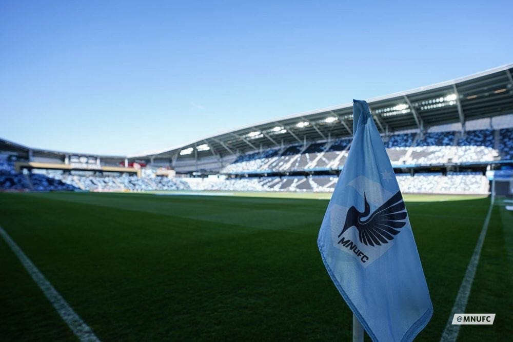 The flag for Minnesota United FC rest along its pool with the field and stands extending behind it.