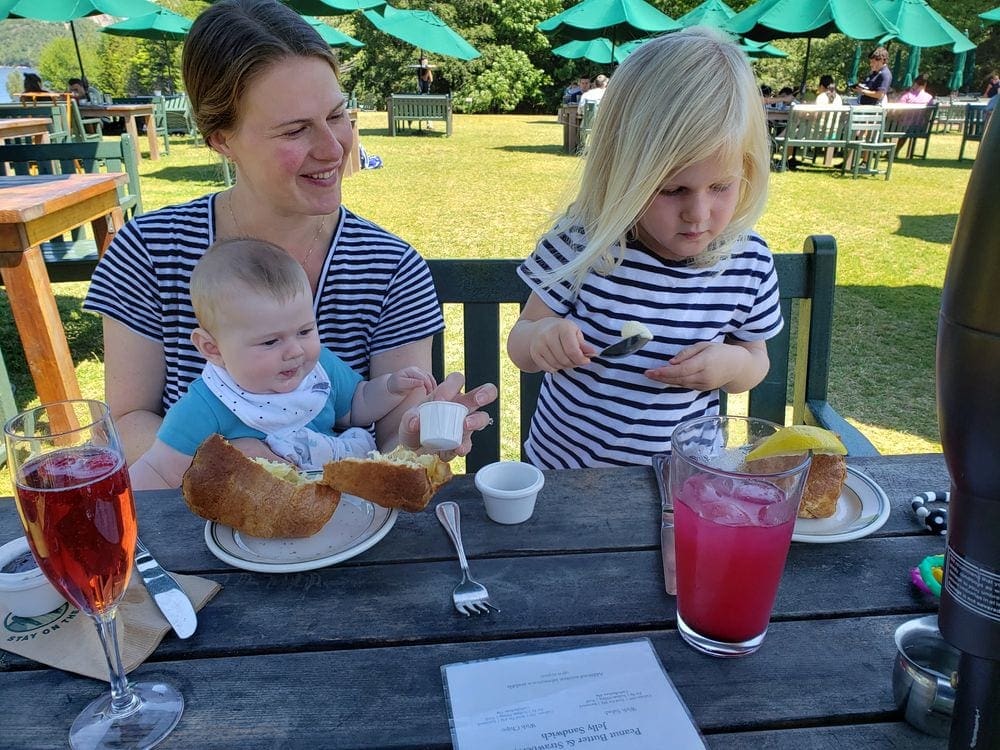 A mom smiles on at her two children as they enjoy a meal at Jordan's Pond House inside Acadia National Park, one of the best things to do in Bar Harbor with kids.