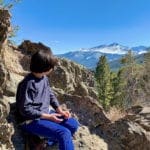 A young boy looks over a sweeping view of Rocky Mountain National Park, one of the best places to visit in Colorado with kids.