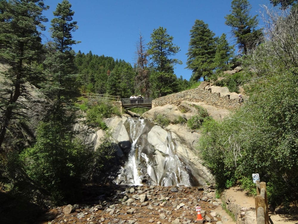 A view of Helen Hunt Falls, surrounded by evergreens and rocks.