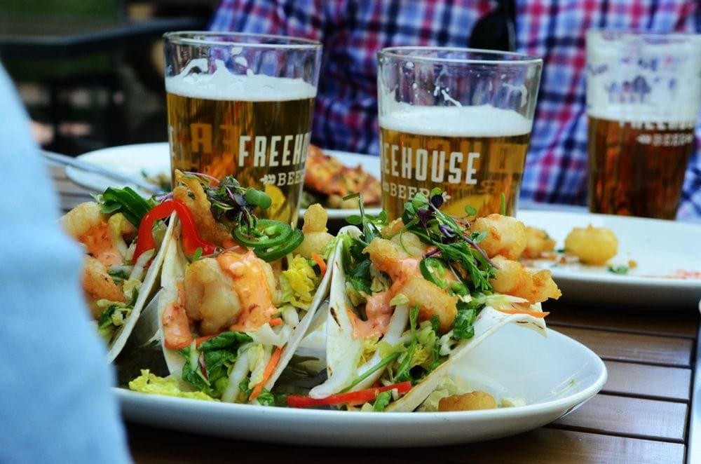 A plate filled with fish tacos, with two pints reading Freehouse in the background.