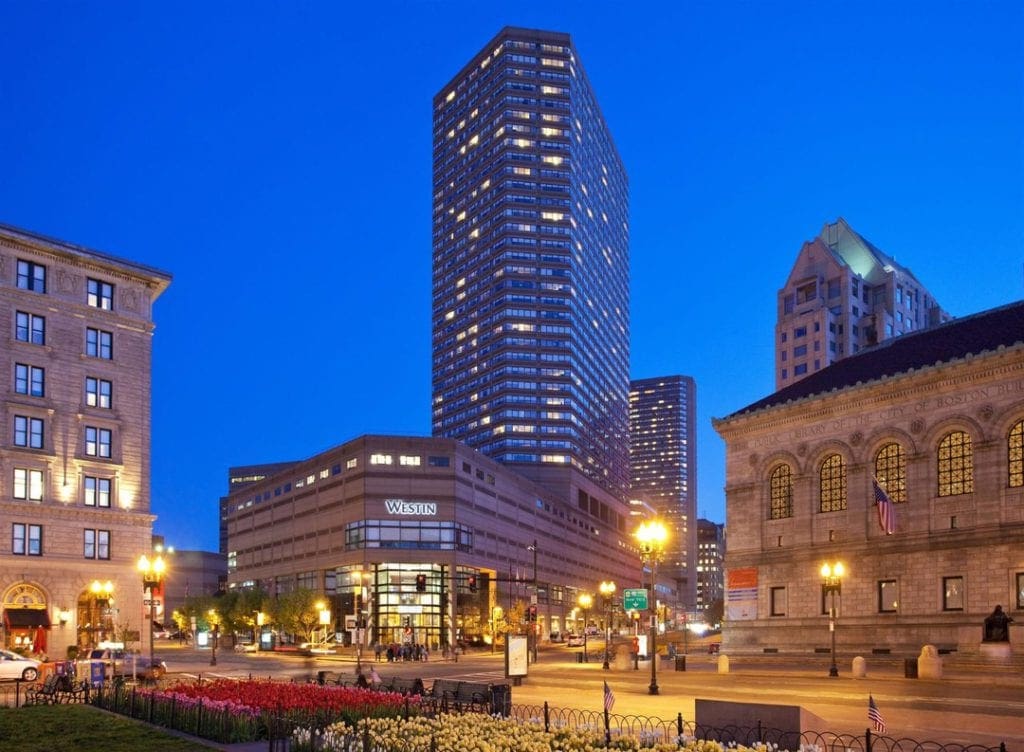 A view of the The Westin Copley Place, one of the best hotels in boston for families, Boston at night surrounded by other towering Boston buildings.