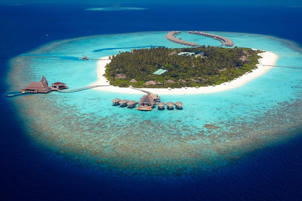 An aerial view of Anantara Kihavah Maldives Villas, one of the best family hotels in the Maldives, showcasing their private island and over-water bungalows.