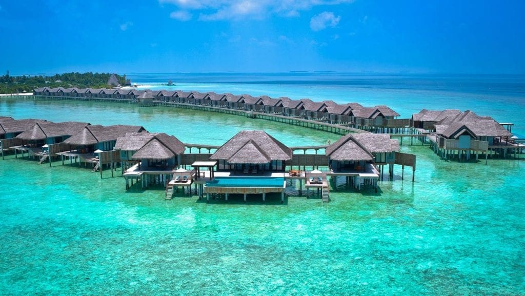 Two lines of over-water bungalows at the Anantara Kihavah Maldives Villas, one of the best family hotels in the Maldives.