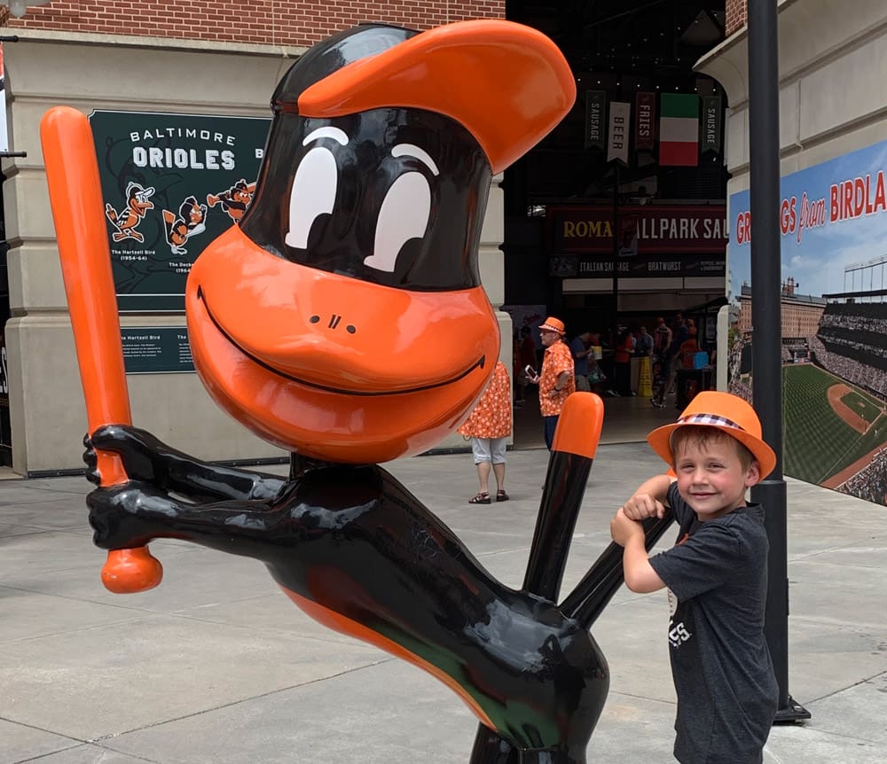A young boy poses with a statue of a mascot duck in Baltimore.