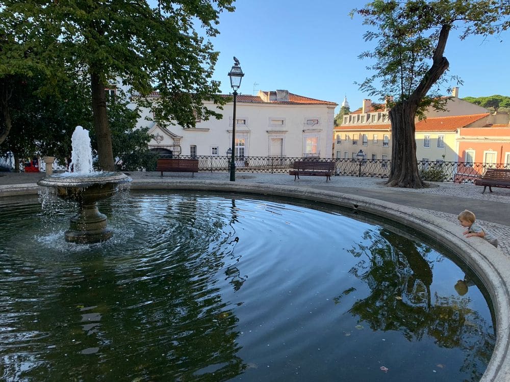 A young boy peers into a fountain in a courtyard in Lisbon.