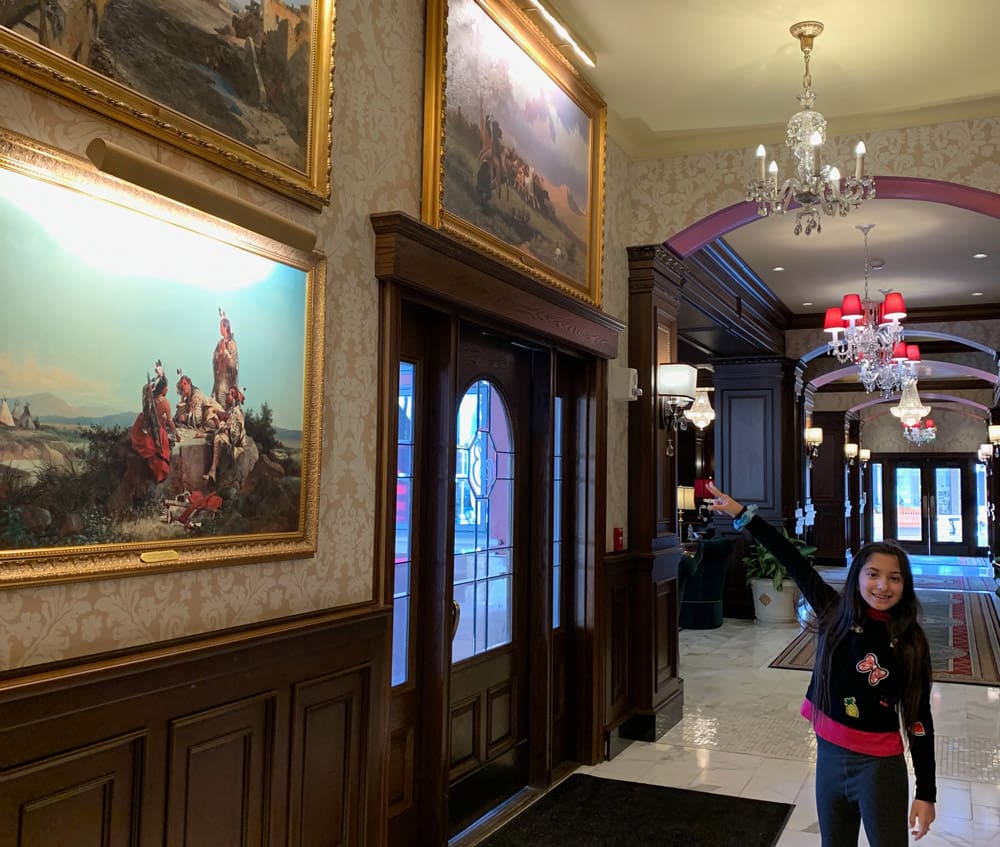 A young girl points at several ornate paintings inside the Broadmoor.