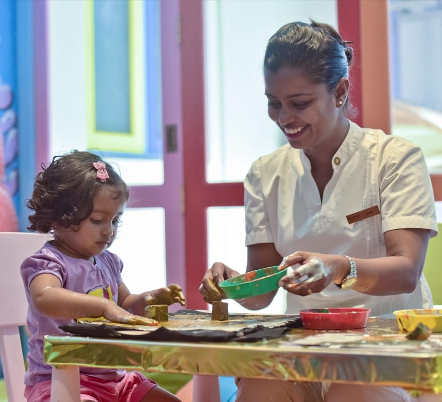 A staff member helps a toddler eat at the Conrad Maldives Rangali Island.