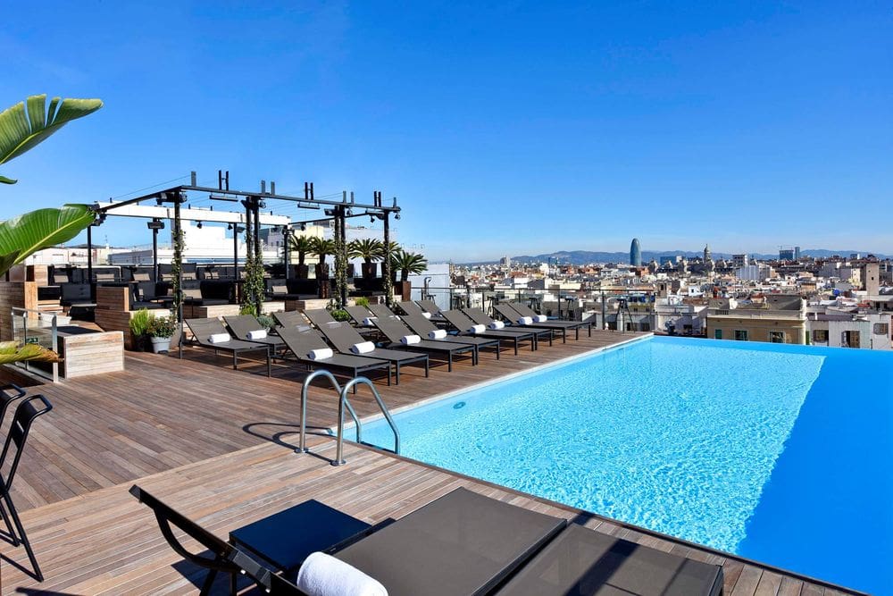 The rooftop pool and nearby loungers at Grand Hotel Central, one of the best family Barcelona hotels.