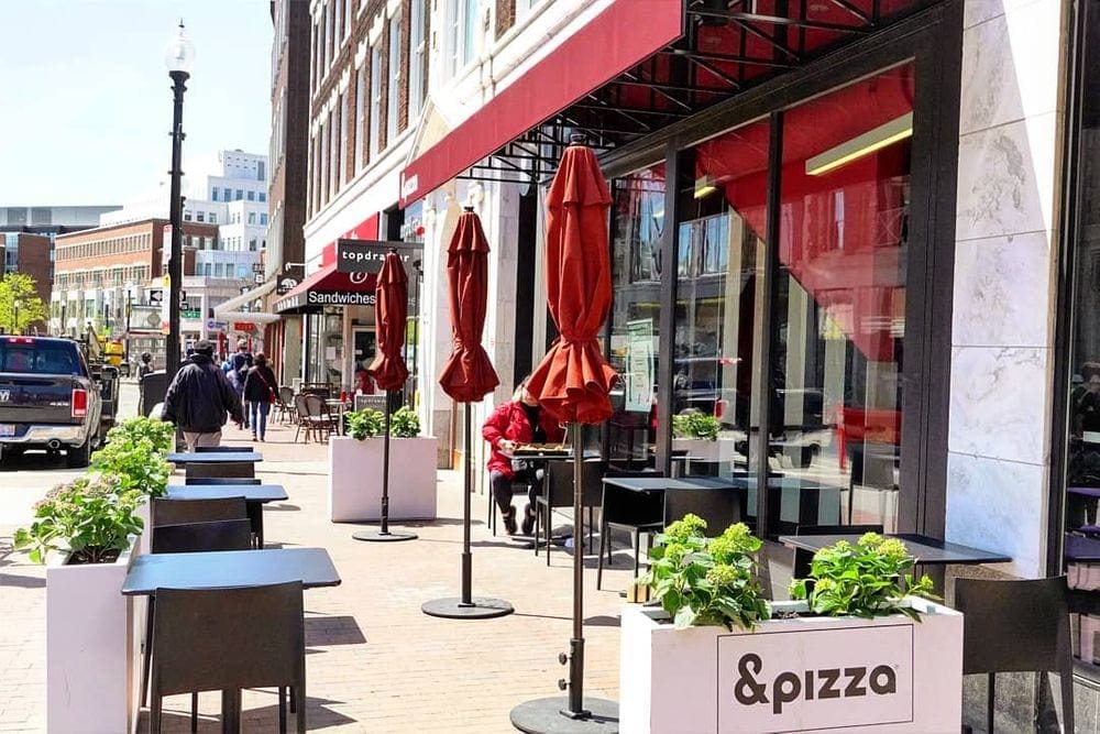 A look down Brattle Street off Havard Square, including outdoor restaurant seating and city views.
