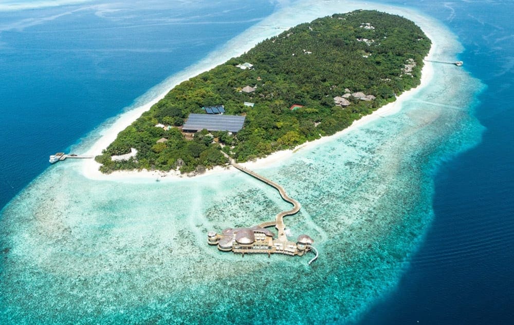 An areial view of the Soneva Fushi, featuring lush ground and immediate ocean acces.