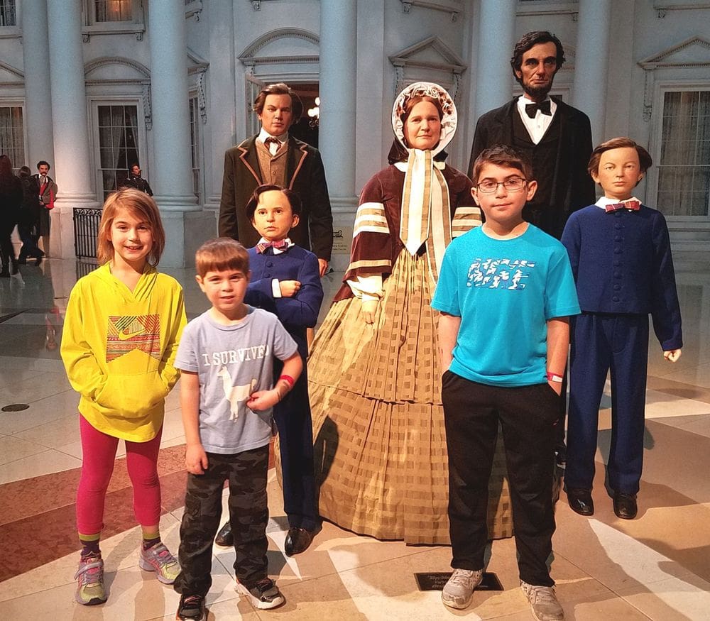 Three kids stand amongst five wax statues of Abraham Lincoln, his wife and three others at the Springfield Lincoln Museum.