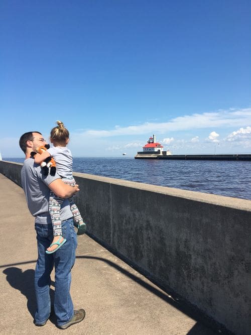 A dad holds his young daughter while walking along the pier viewing Lake Superior in Duluth, Minnesota.
