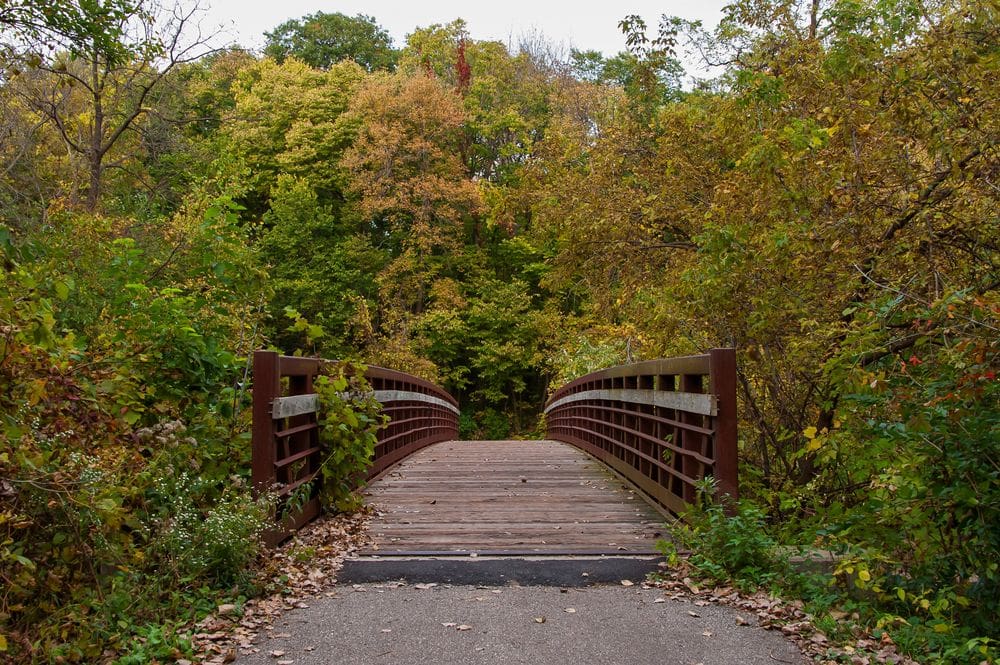 A bridge within Brookside Park shrouded in a fall leaves and foliage in Ames, Iowa, one of the weekend getaways from Minneapolis for families.