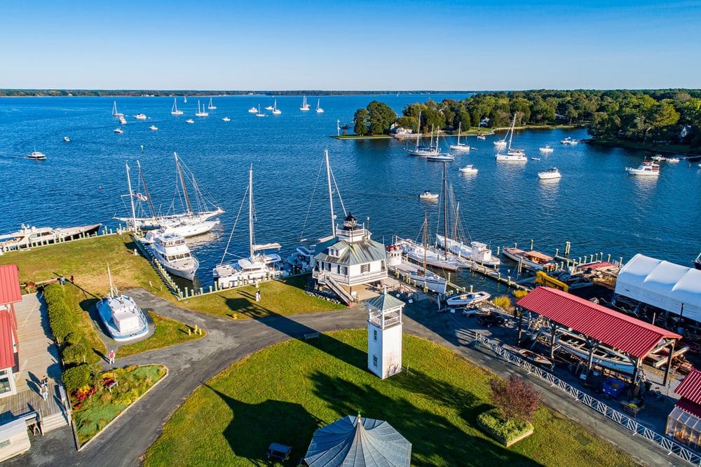 An aerial view of the Chesapeake Bay Maritime Museum, along the water, featuring boats and lush foliage.