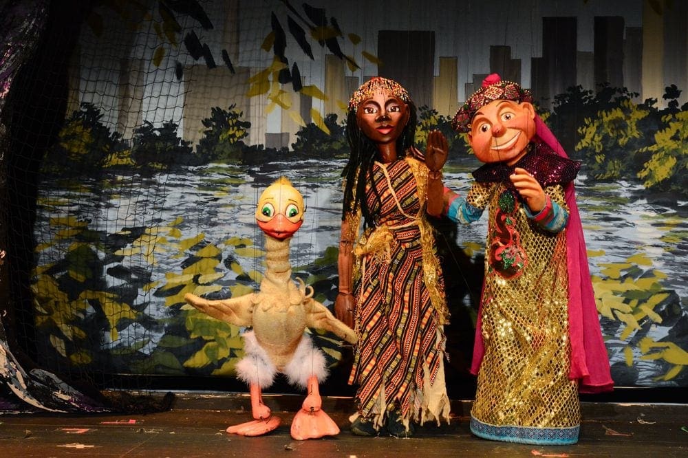 Three puppets, two people and one duck, on stage at a production for the Swedish Cottage Marionette Theater, one of the best indoor activities in New York City for kids.