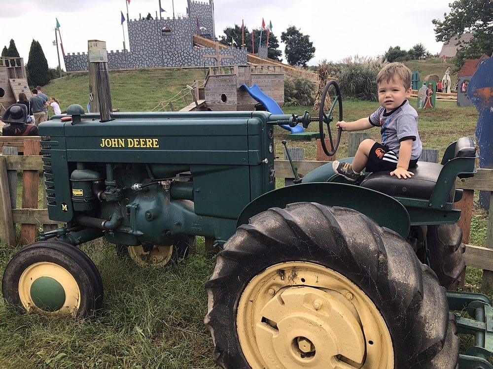 A young boy sits on a tractor while exploring Cox Farms, a great location for fall activities near Washington DC for families.