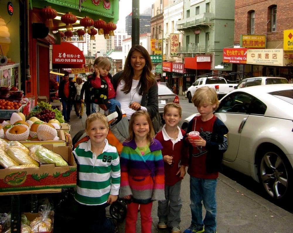 A mom stands with five kids on a street in Chinatown.