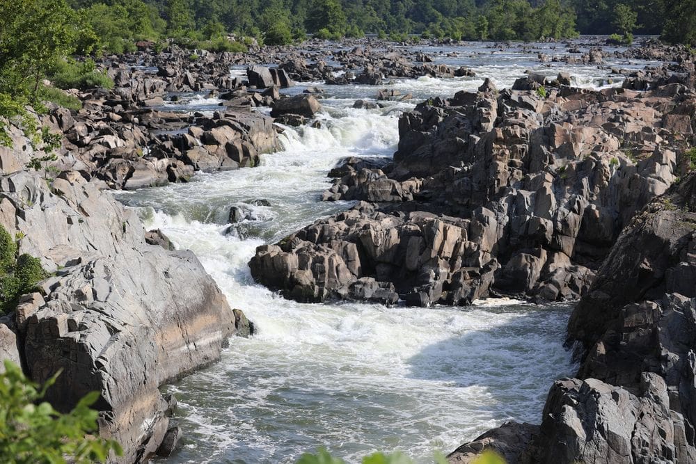 A view of the rushing river through jagged rocks at Great Falls Park.