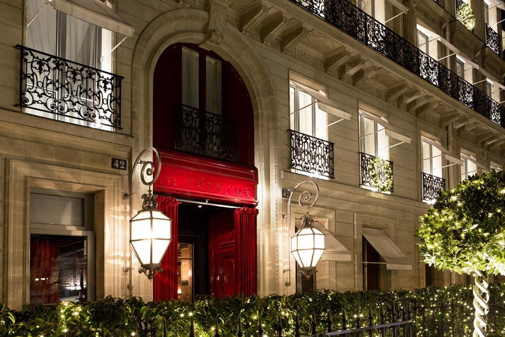 The lit-up entrance to La Réserve Paris Hotel and Spa at night.