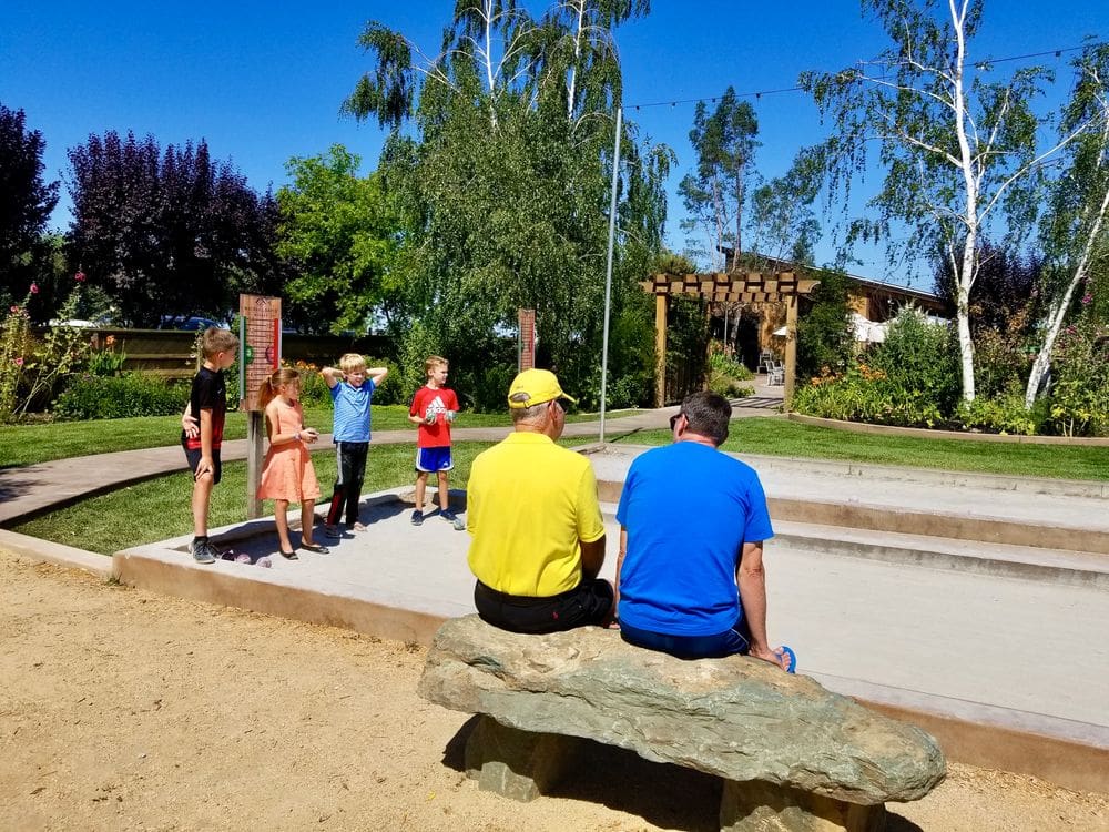 Kids play Bocce Ball while two adults look on while exploring Lodi, one of the best Bay Area weekend getaways with kids.