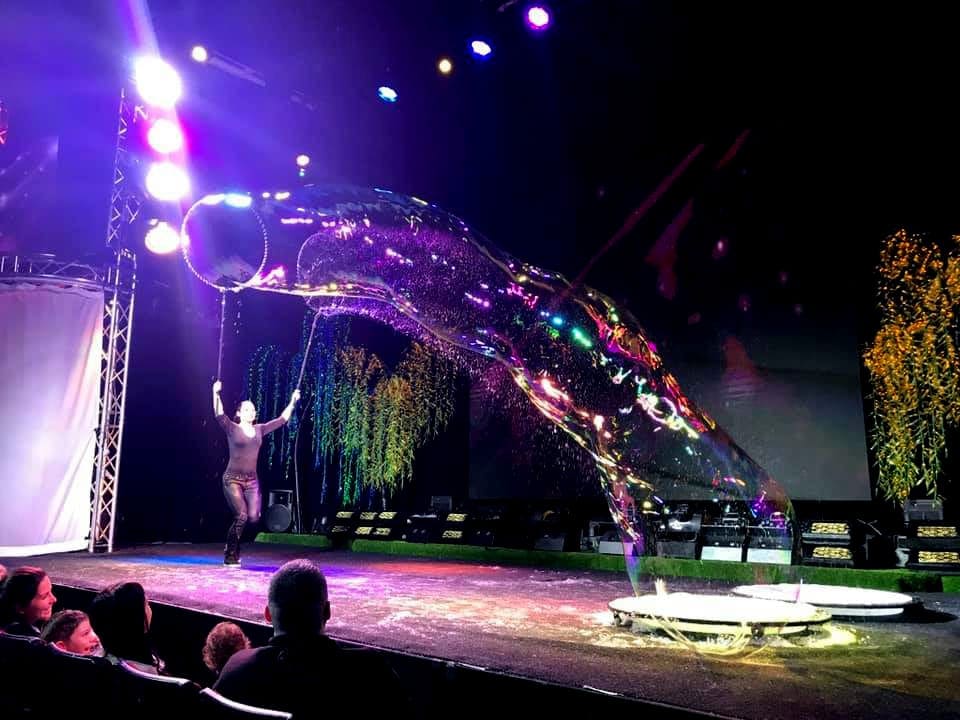 A performer on stage creates a huge bubble during the Gazillion Bubble Show.