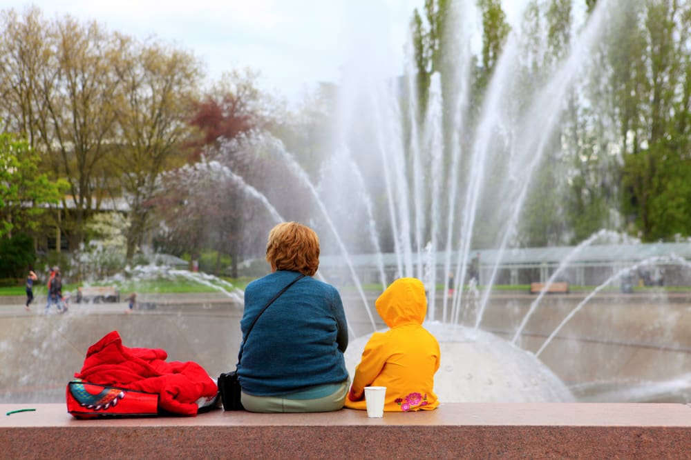 Grandma and kid sitting facing the fountain in Seattle, Washington.