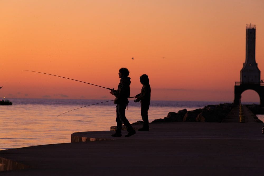 Two young boys fish along the pier in Port Washington at sunset, one of the best places to visit in Wisconsin for families.