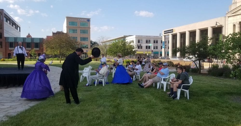 Several onlookers enjoy a show featuring actors playing Mary Todd Lincoln and Abraham Lincoln outisde on a sunny day in Springfield, Illinois.
