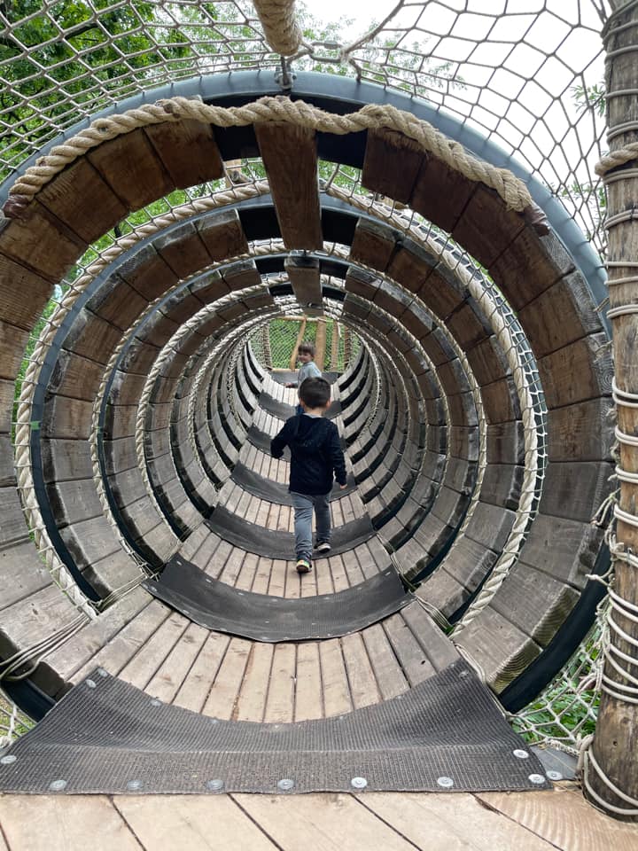 A young boy walks through a wooded tunnel while exploring the Bronx Zoo.