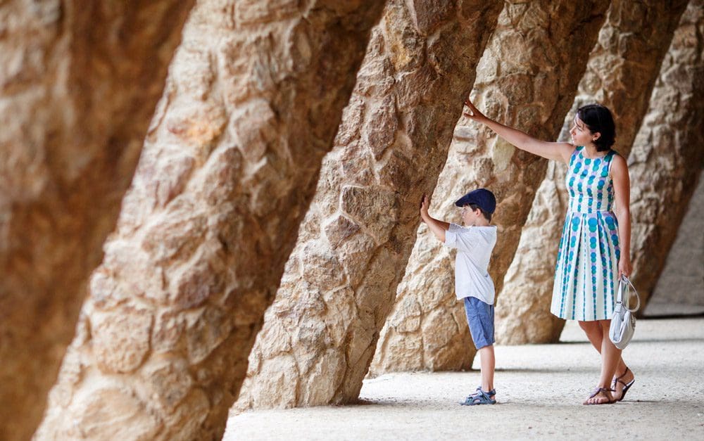 A mom and her young son touch a large stone wall while exploring Spain.