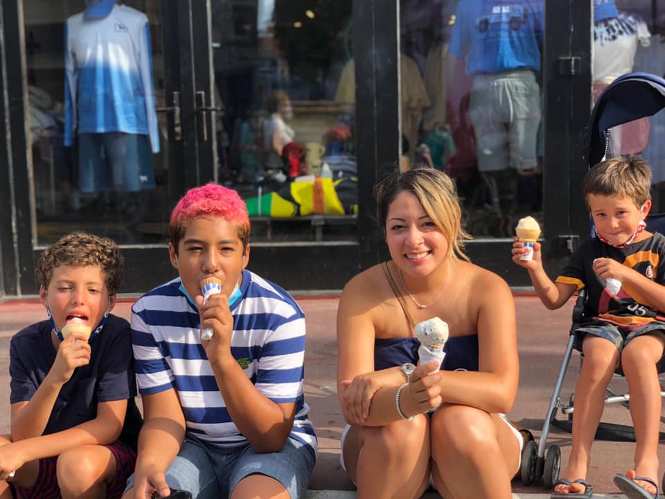 Four kids sitting on the curb enjoy an ice cream cone in Provincetown, one of the best Fourth of July destinations for a family trip.