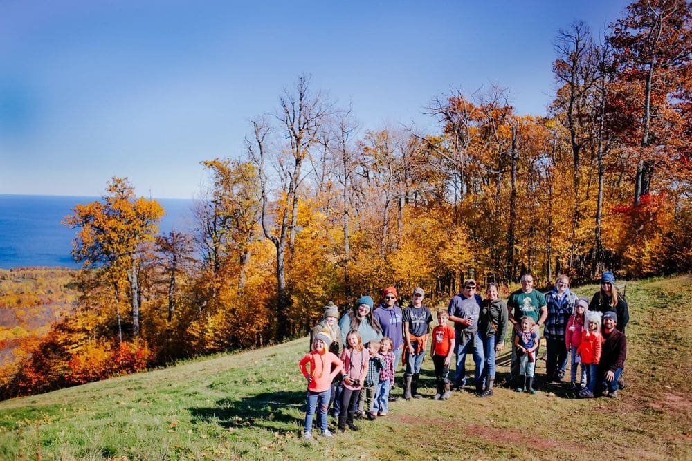 A large family stands amongst fall foliages in the Porcupine Mountains in Michigan, one of the best places to see fall colors in the Midwest for families.