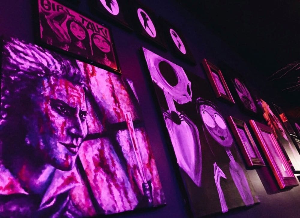 Inside Beetle House, displayed artwork in hues of purple, pink, and red on the wall.