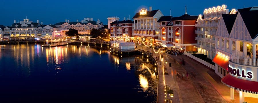 The Disney’s Boardwalk Resort at night, lit up with lights shimmering on the water, one of the best places to stay for the holidays in Disney as a family.