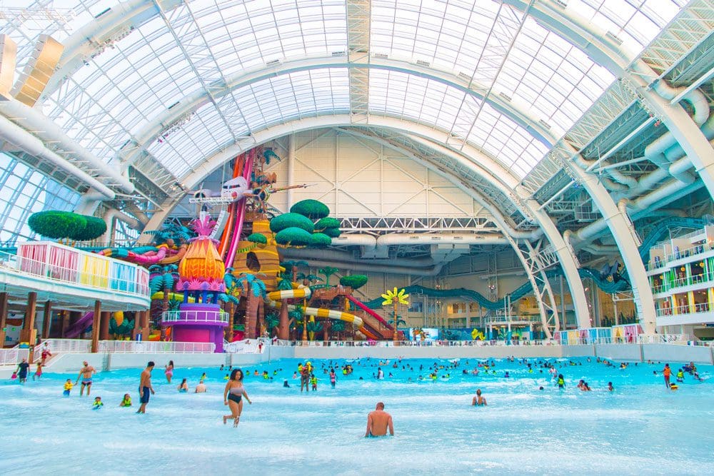 Inside the indoor waterpark at DreamWorks Water Park, featuring colorful slides and several swimmers.