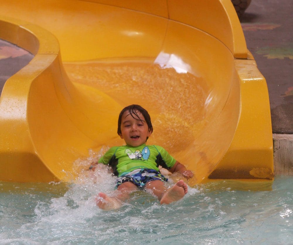 A young boy chutes down a yellow water slide at the Great Wold Lodge.