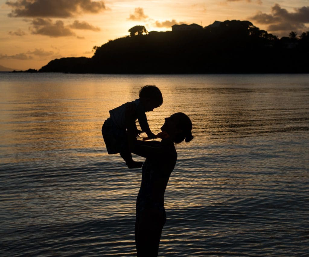 silhouette of mom and son in a beach in Antigua, one of the best affordable Caribbean islands for families 